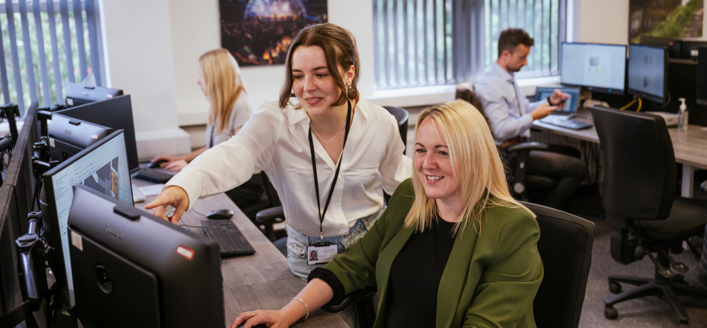Two ladies discussing work whilst looking at computer screens