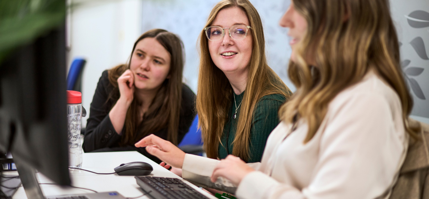 A group of ladies viewing work on a computer screen at a desk
