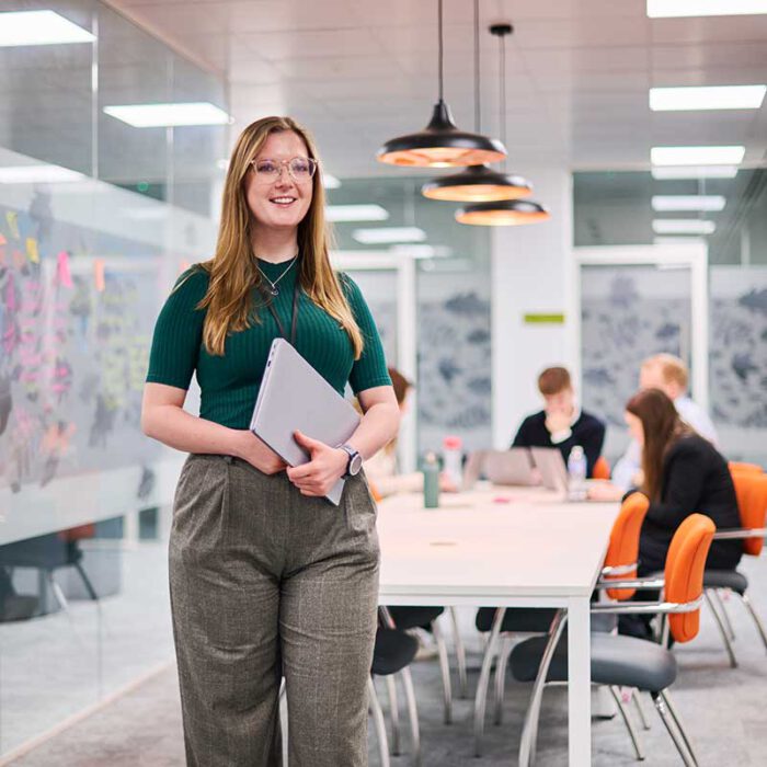 Girl standing in office with closed laptop in her hands