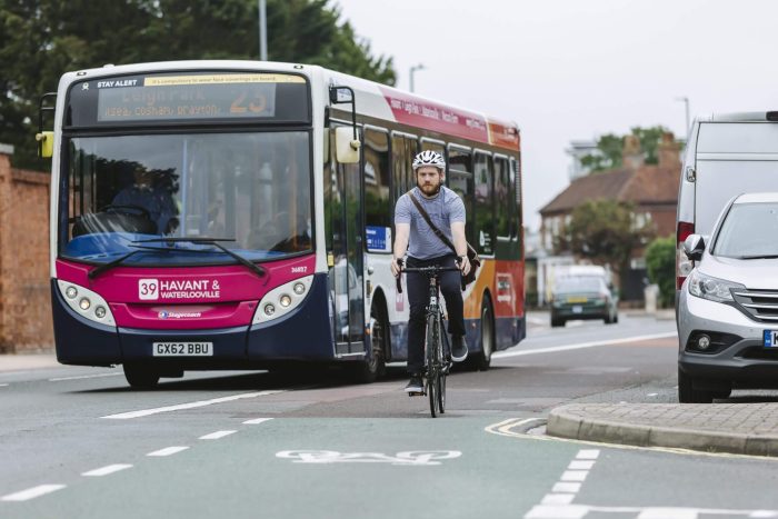 a cyclist in a cycle lane, passing a bus